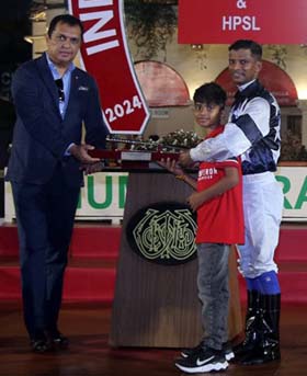 Sandesh who emerged as the Champion Jockey at the end of the Mumbai Racing Season receiving the trophy along with his son from Gautam Lala, Steward of Royal Western India Turf Club at Mumbai on Sunday.